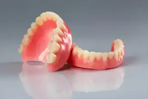 Full upper and lower dentures displayed on a reflective dental surface